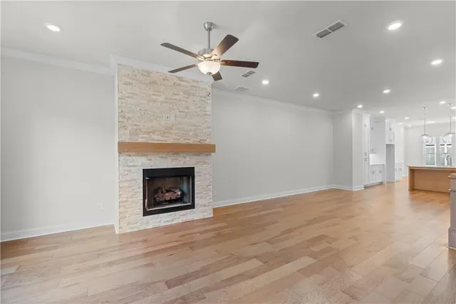 a view of a room with wooden floor a ceiling fan a fireplace and window