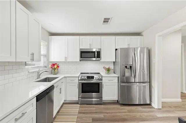 a kitchen with a sink a microwave a refrigerator and cabinets