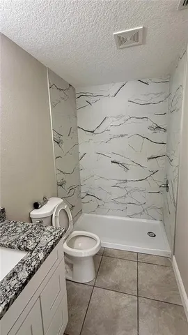 a bathroom with a granite countertop sink toilet and shower