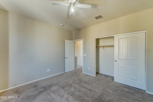 an empty room with a chandelier fan and closet area
