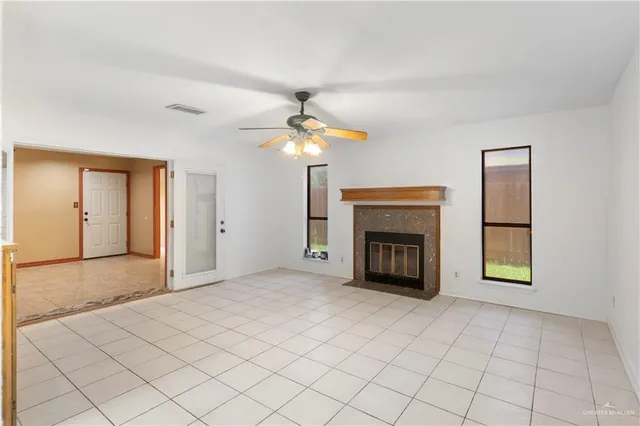 a view of an empty room with a fireplace and a chandelier fan