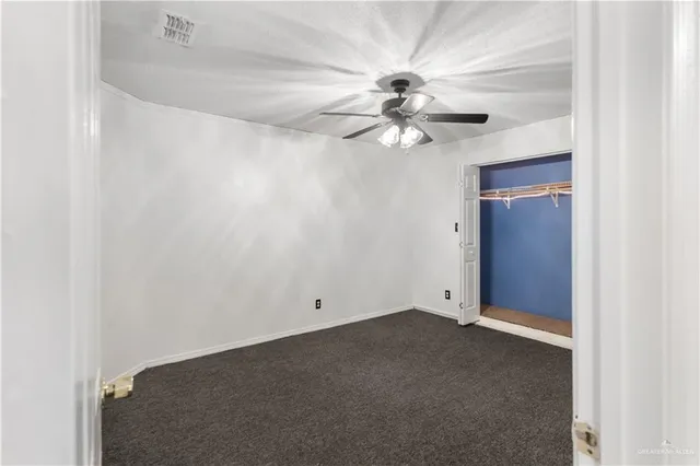 an empty room with a fan & a ceiling fan