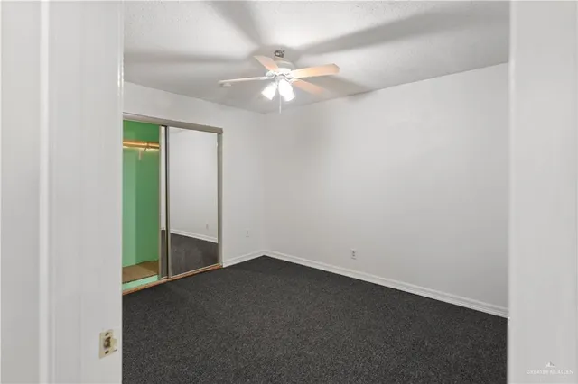 an empty room with a chandelier fan and windows