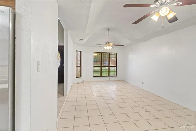an empty room with chandelier fan and windows