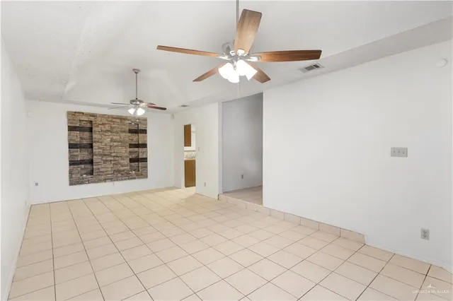 a view of an empty room with chandelier fan and window