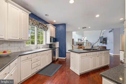 a kitchen with refrigerator a stove a sink and white cabinets with wooden floor