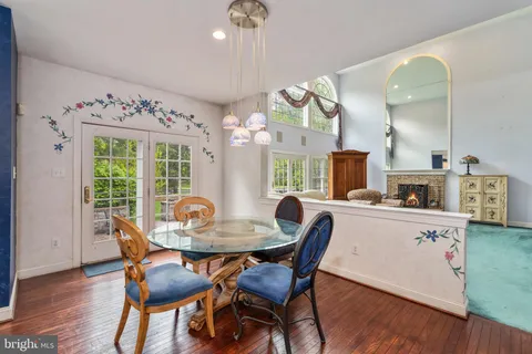 a kitchen with stainless steel appliances granite countertop a stove top oven a refrigerator a dining table and chairs with wooden floor