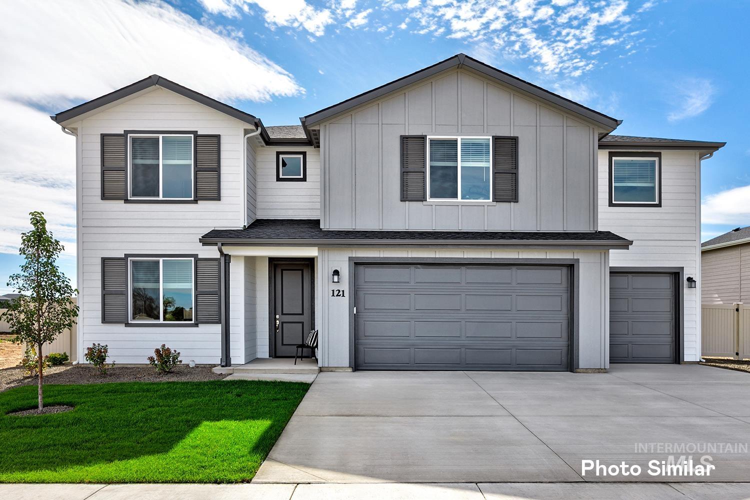 View of front of property featuring a garage, driveway, a front lawn, board and batten siding, and roof with shingles
