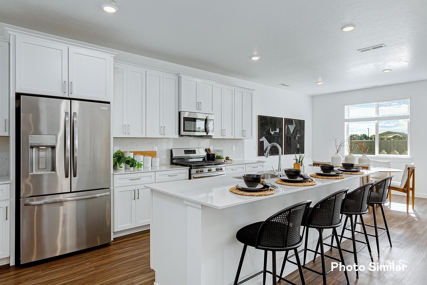 220 Ravello Street Caldwell, ID 83605 - Photo 12 of 35 Kitchen with appliances with stainless steel finishes, white cabinetry, a kitchen island with sink, dark wood-style flooring, and recessed lighting