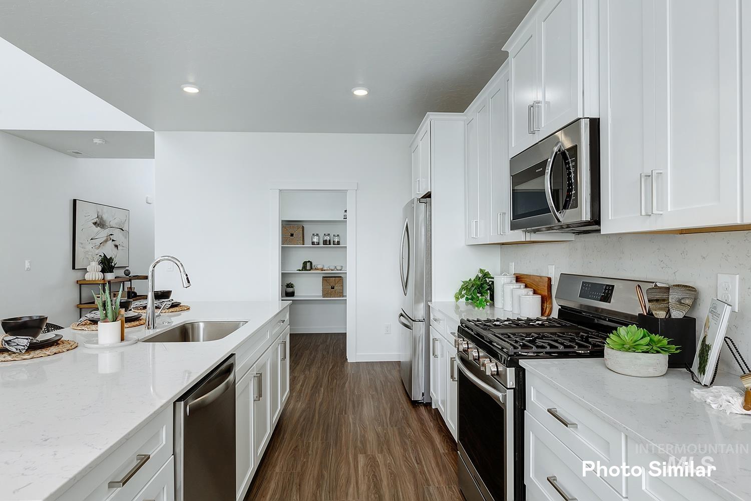 220 Ravello Street Caldwell, ID 83605 - Photo 14 of 35 Kitchen featuring light stone counters, stainless steel appliances, dark wood-type flooring, white cabinetry, and recessed lighting
