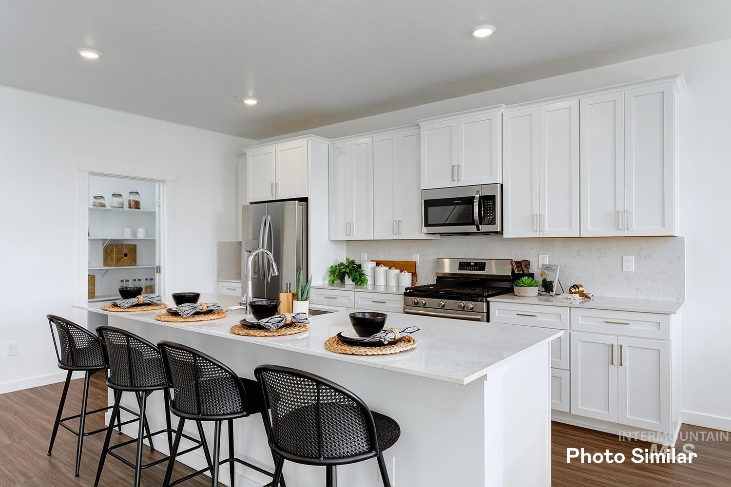 220 Ravello Street Caldwell, ID 83605 - Photo 10 of 35 Kitchen with dark wood-type flooring, white cabinets, appliances with stainless steel finishes, a breakfast bar, and recessed lighting