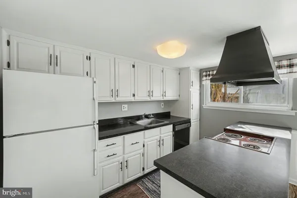 a kitchen with granite countertop a refrigerator a stove a sink and white cabinets