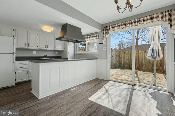 a kitchen with granite countertop a stove a sink and white cabinets with wooden floor
