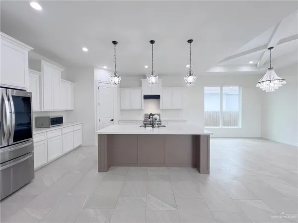 a large white kitchen with kitchen island a stove a sink a refrigerator and a refrigerator