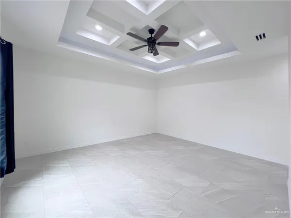 an empty room with chandelier fan and windows