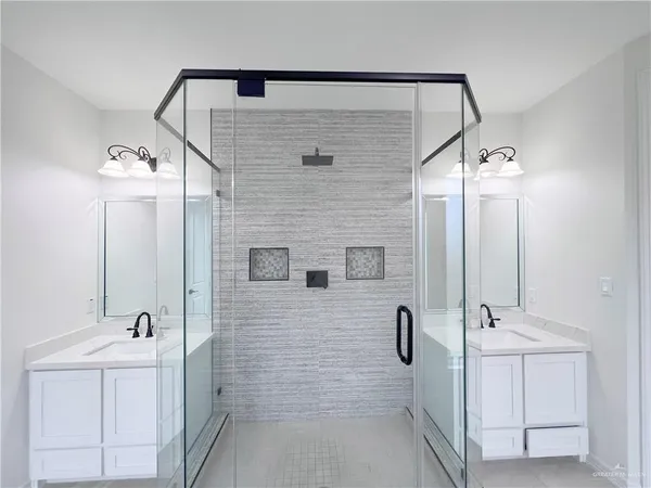 a bathroom with a double vanity sink mirror and shower