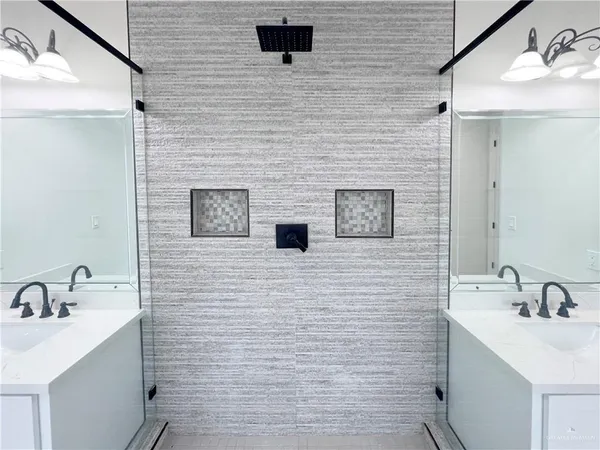 a bathroom with a double vanity sink mirror and shower