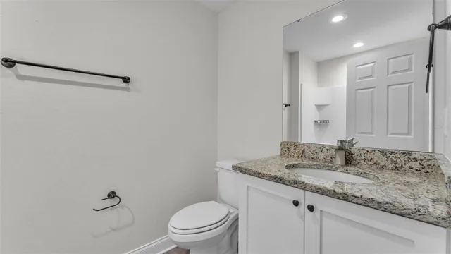 a bathroom with a granite countertop sink a toilet and a mirror