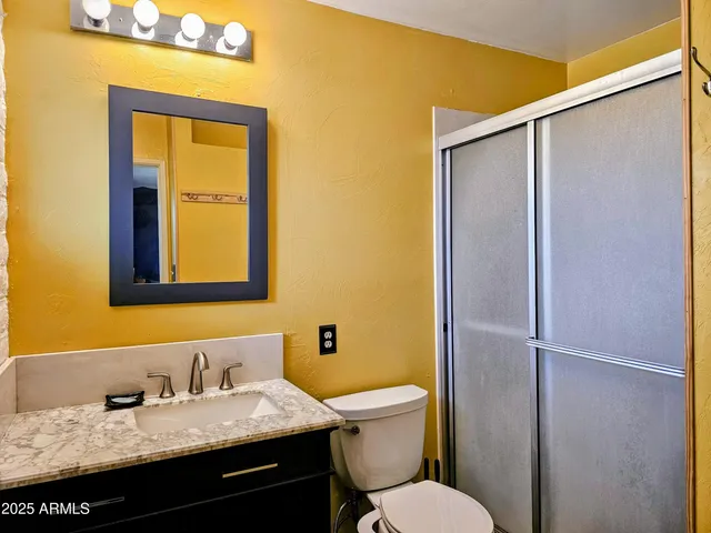 a bathroom with a granite countertop sink toilet and mirror