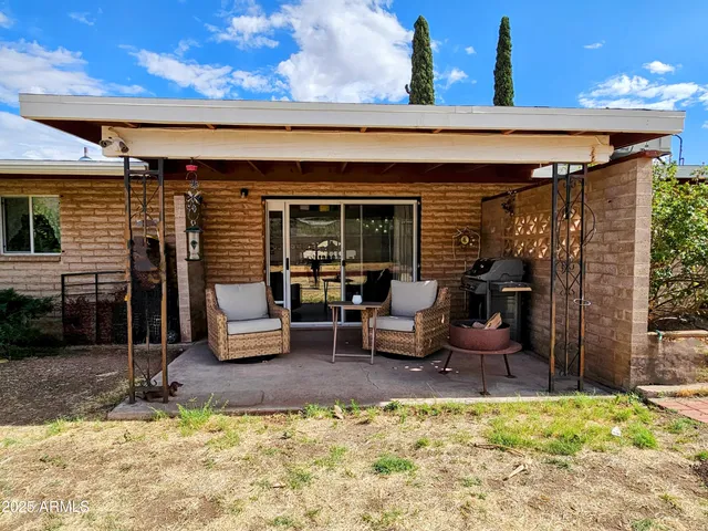 a view of a patio with table and chairs near a barbeque grill
