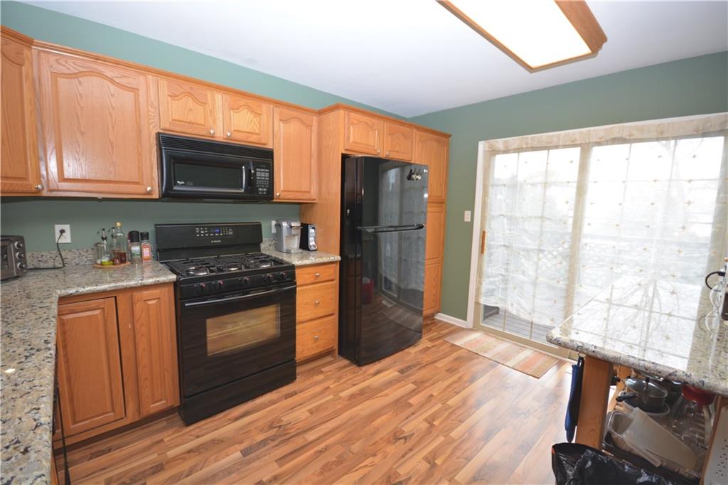 218 Grace Street McKees Rocks, PA 15136 - Photo 8 of 22 Newer gas stove and refrigerator. Laminate wood flooring continues in the kitchen. Sliding door to patio from kitchen.