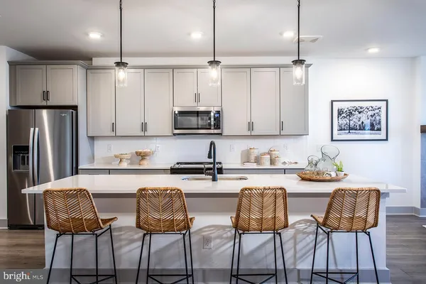 a kitchen with stainless steel appliances kitchen island granite countertop a dining table chairs and white cabinets