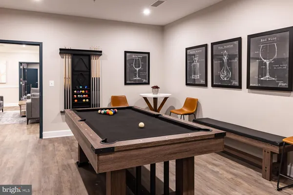 a living room with furniture pool table and wooden floor