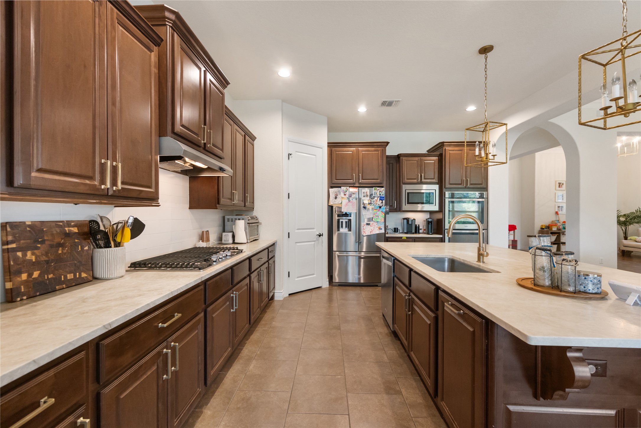 415 Bitterroot Lane Austin, TX 78737 - Photo 4 of 25 Culinary delights await in this chef's kitchen, featuring warm wood cabinetry and a central island with sink.