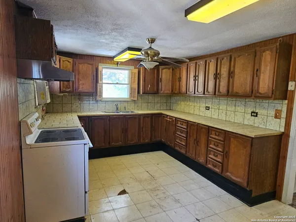 a kitchen with a sink a stove cabinets and a window