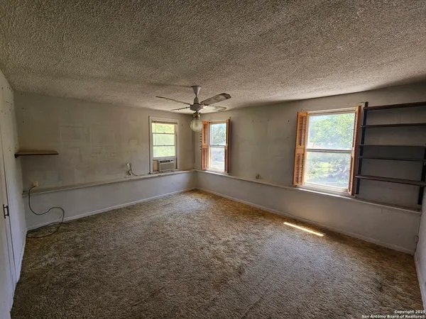 en empty room with windows and ceiling fan