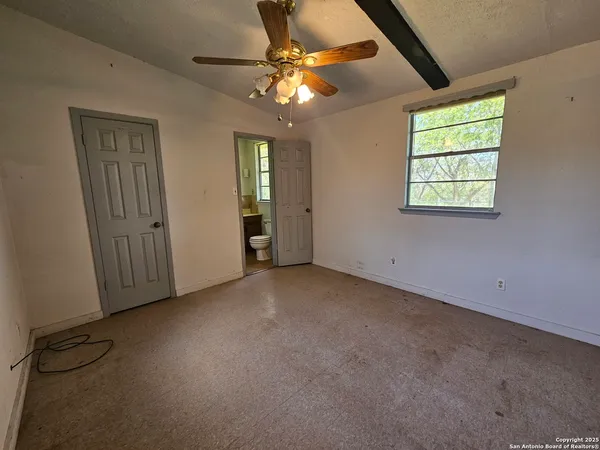 an empty room with windows and fan