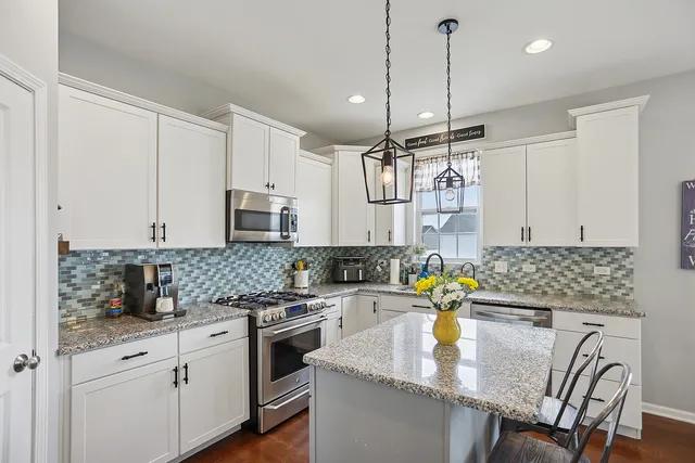 a kitchen with kitchen island granite countertop a sink a counter space appliances and cabinets