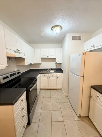 a white kitchen with granite top and stainless steel appliances