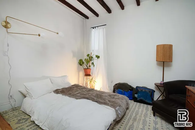 a bedroom with a bed and a lamp with the wooden floor