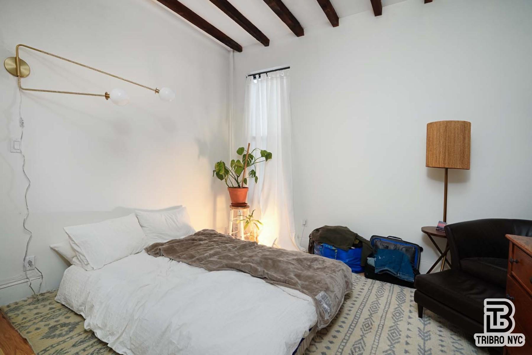 60-42 Grove Street, Unit 2R Queens, NY 11385 - Photo 2 of 7 a bedroom with a bed and a lamp with the wooden floor