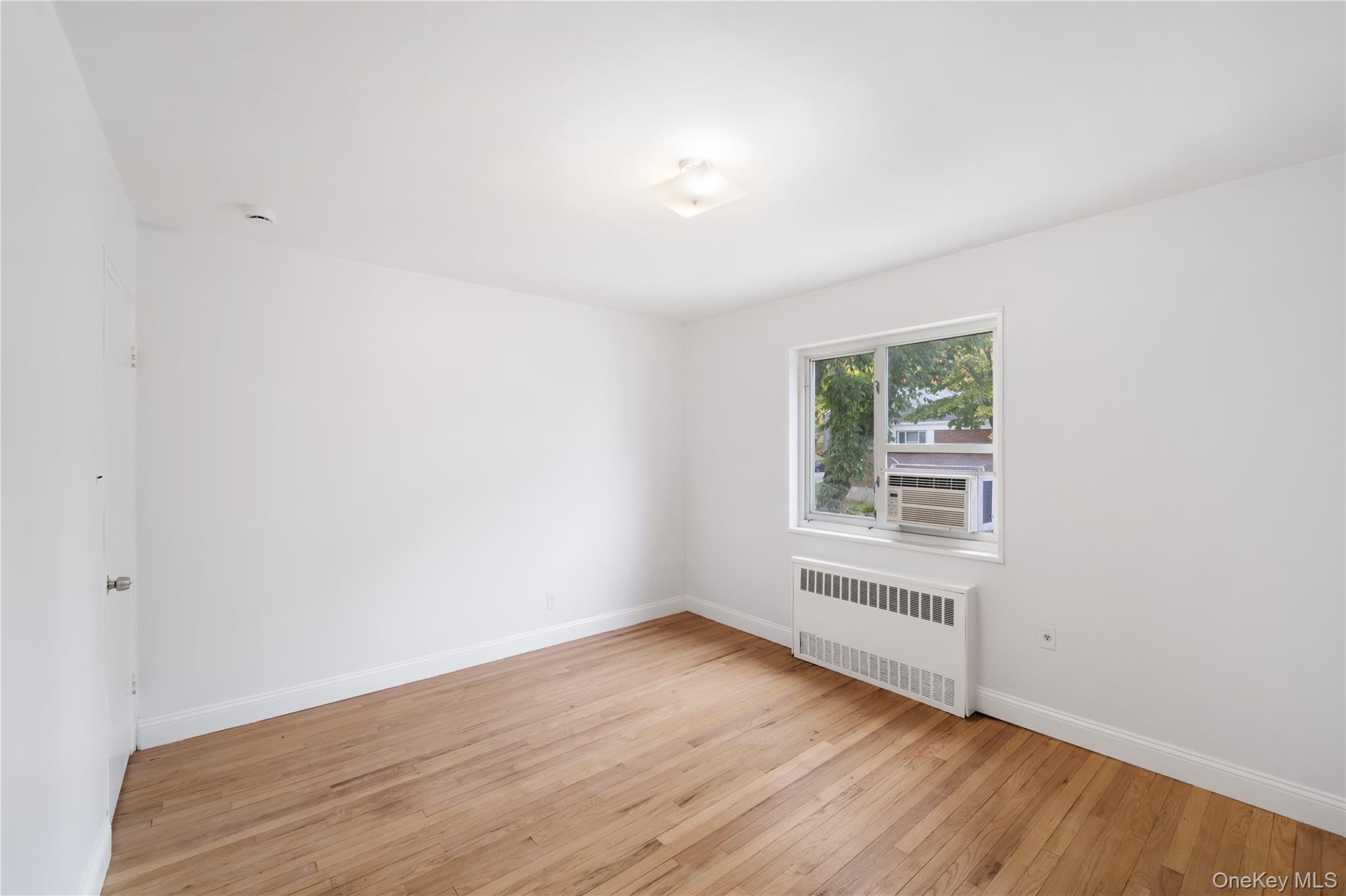 221-26 Manor Road, Unit 116 Queens, NY 11427 - Photo 14 of 19 an empty room with wooden floor and windows
