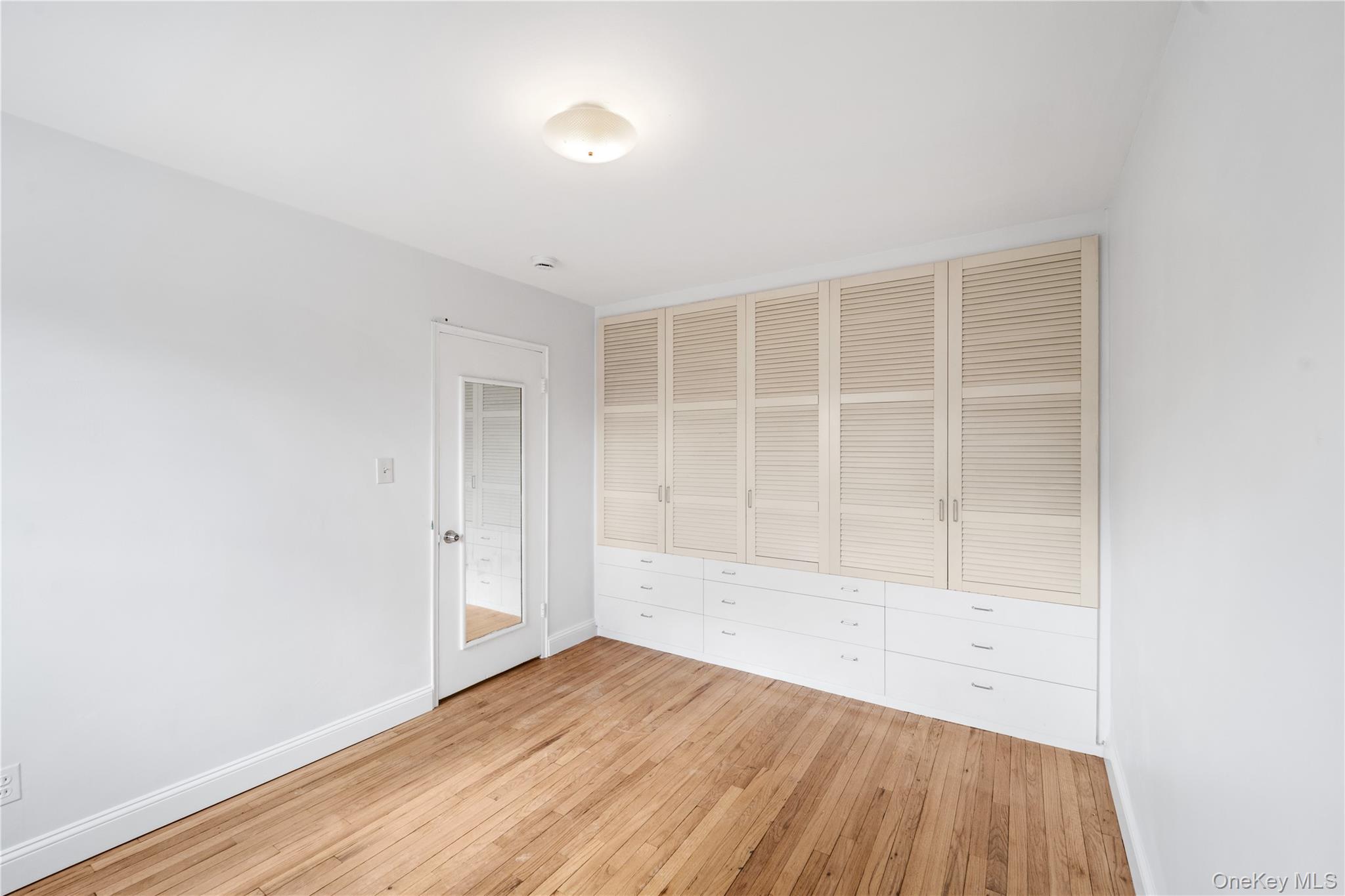 221-26 Manor Road, Unit 116 Queens, NY 11427 - Photo 16 of 19 an empty room with wooden floor and windows