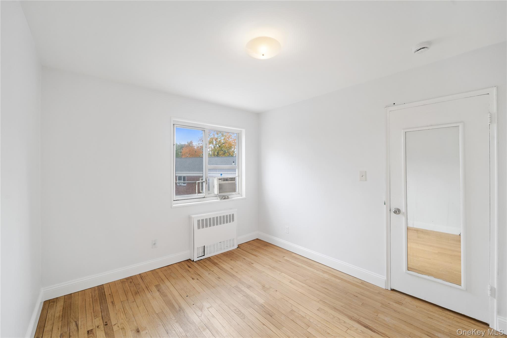 221-26 Manor Road, Unit 116 Queens, NY 11427 - Photo 17 of 19 an empty room with wooden floor and windows