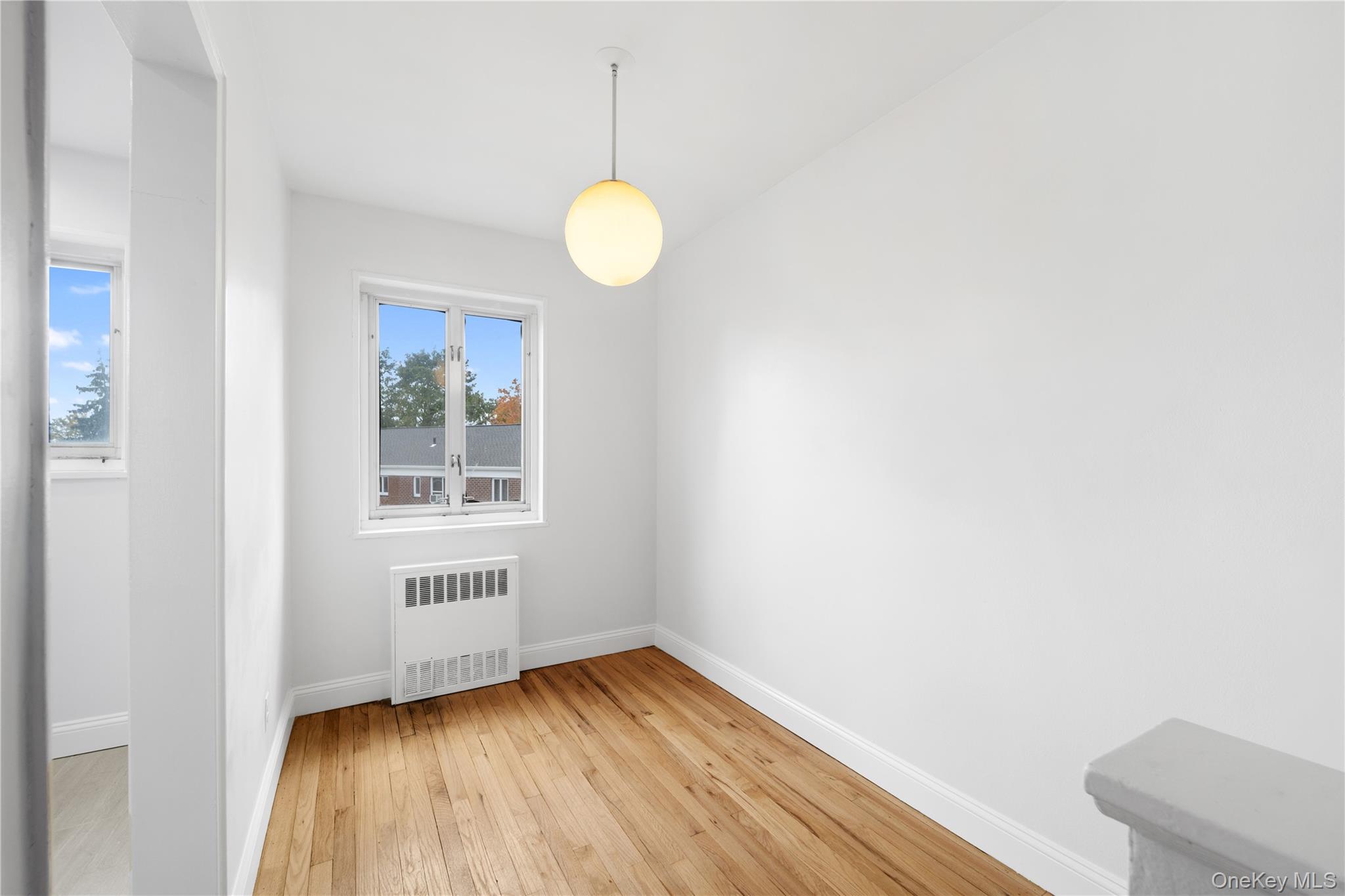 221-26 Manor Road, Unit 116 Queens, NY 11427 - Photo 5 of 19 an empty room with wooden floor and windows