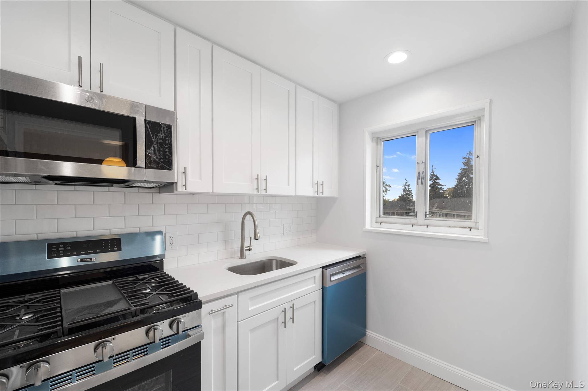 221-26 Manor Road, Unit 116 Queens, NY 11427 - Photo 7 of 19 a kitchen with stainless steel appliances a stove a microwave and sink