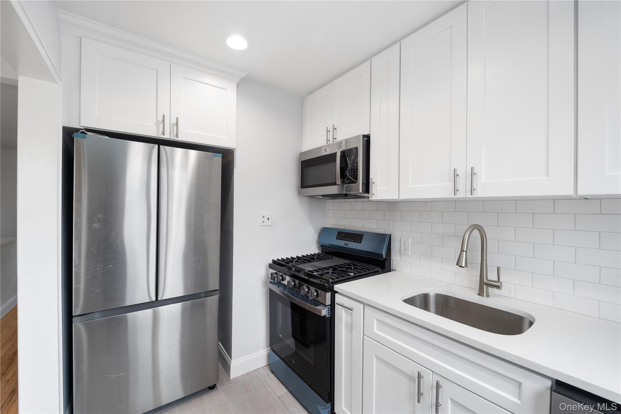 221-26 Manor Road, Unit 116 Queens, NY 11427 - Photo 8 of 19 a kitchen with stainless steel appliances a refrigerator sink and microwave