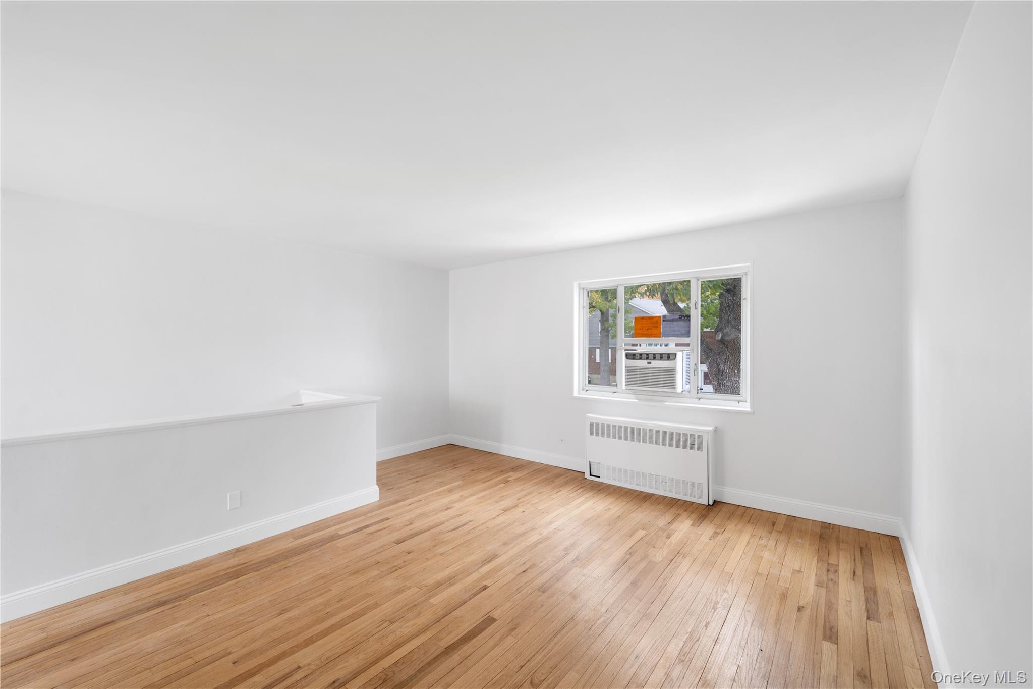 221-26 Manor Road, Unit 116 Queens, NY 11427 - Photo 9 of 19 an empty room with wooden floor and windows