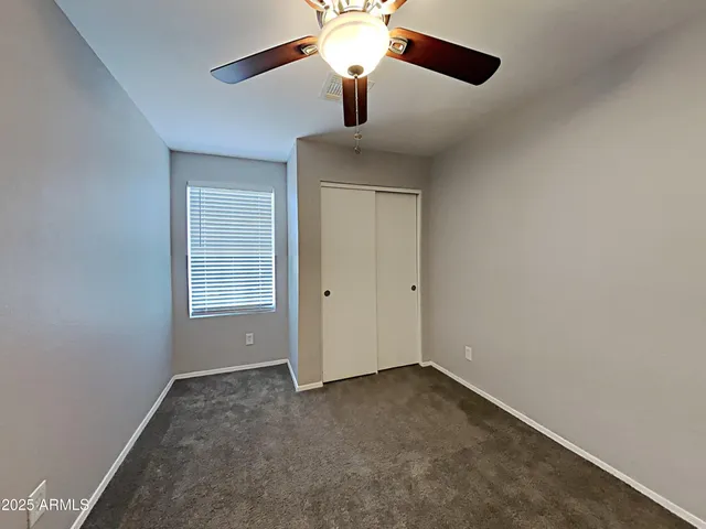 an empty room with windows and chandelier fan