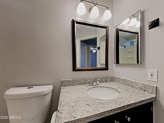 a bathroom with a granite countertop sink and a mirror with toilet