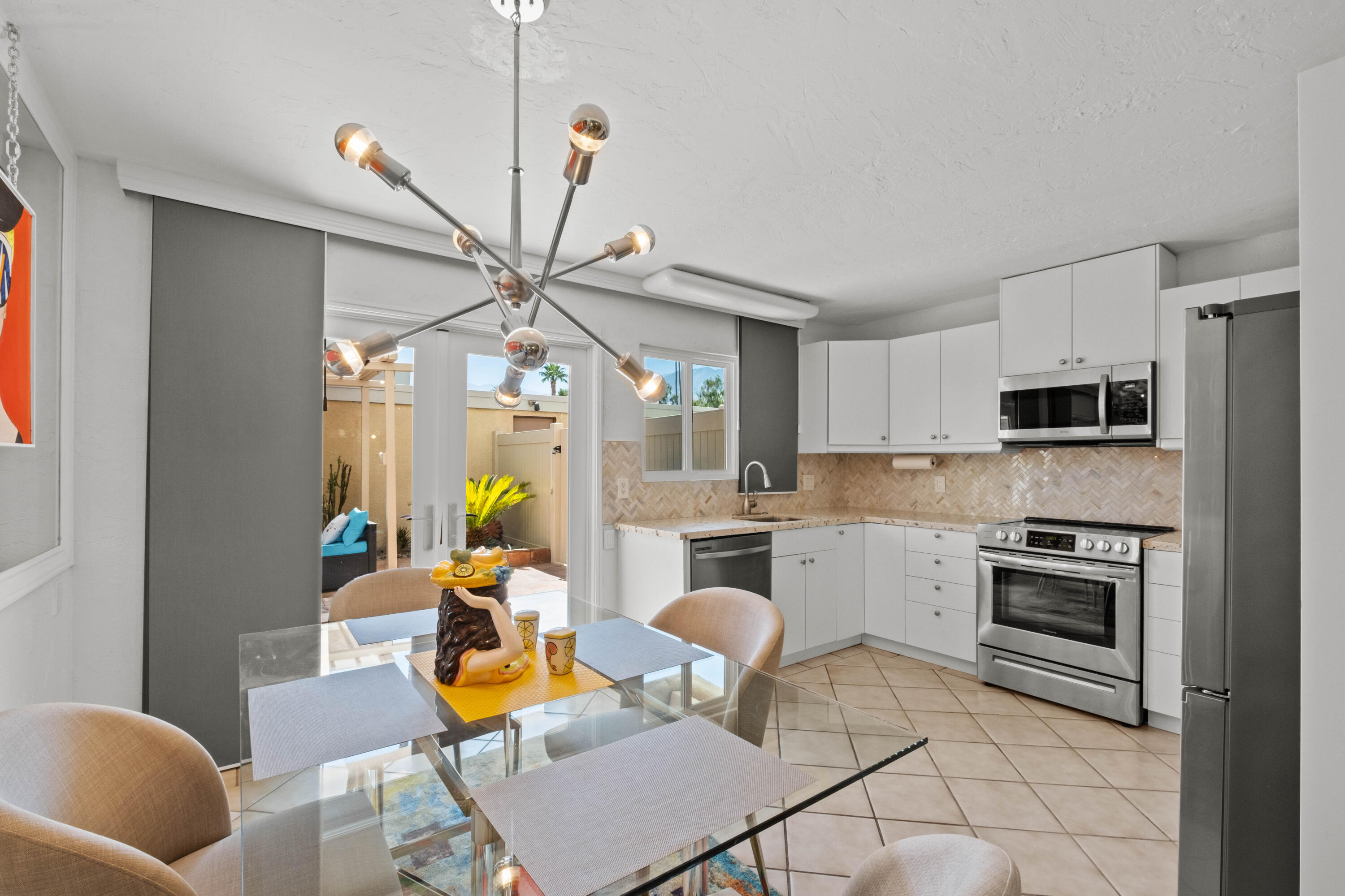1268 Ramon Road, Unit 61 Palm Springs, CA 92264 - Photo 6 of 18 a kitchen with stainless steel appliances a stove a sink cabinets dining table and chairs