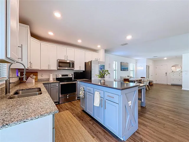 a kitchen with stainless steel appliances granite countertop a refrigerator a sink dishwasher a stove and a refrigerator with wooden floor