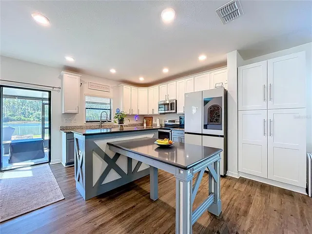 a kitchen with granite countertop kitchen island a sink appliances cabinets and a counter top space