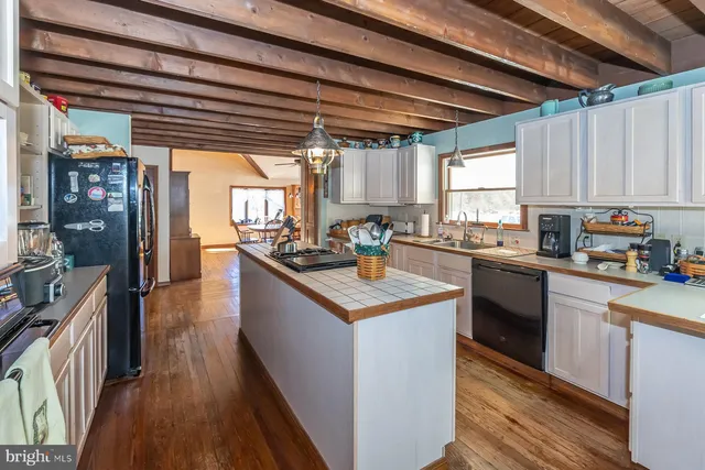 a kitchen with stainless steel appliances granite countertop a stove a sink dishwasher a refrigerator and white cabinets with wooden floor