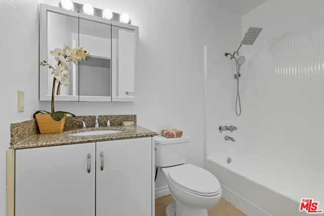 a bathroom with a granite countertop sink a toilet and a mirror