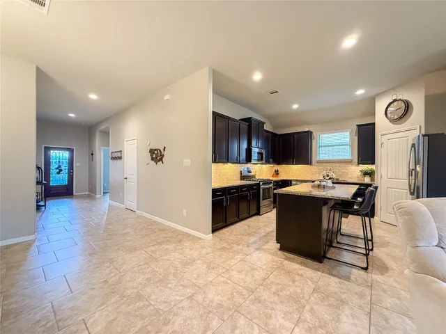 a kitchen with stainless steel appliances kitchen island granite countertop a refrigerator a sink and wooden cabinets